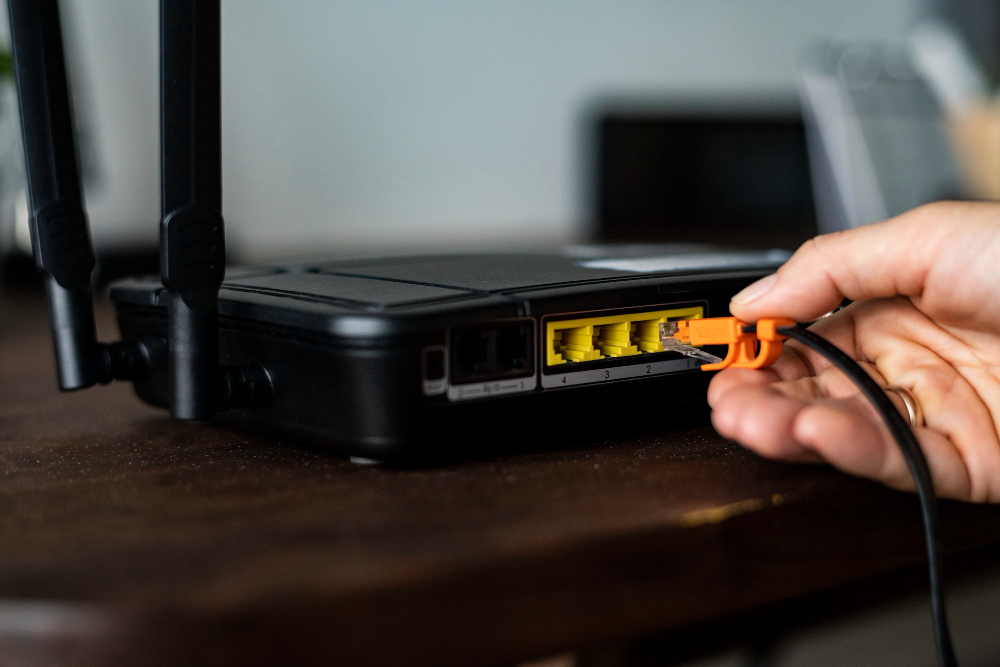 a hand plugging a network cable into a router after a fibre installation in cape town is complete 